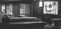 Calligraphy can be seen on the walls, lantern, and noren inside a building, full of low tables.