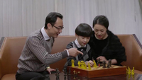 A cozy scene of Feng Teng, as a boy of six or seven playing chess with his parents while seated on an expensive-­looking sofa. Feng is wearing a bow tie. His father wears a gold wristwatch, and there is a pearl necklace around his elegantly dressed mother’s neck.