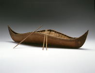 A color photograph of a model of a Beothuk canoe with two paddles and a pole.