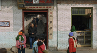 People walk out and through a doorway and alley, framed by calligrapic signs.