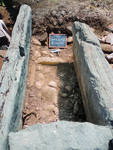 Photograph of the cist grave at tumulus 099. A small chalkboard reads “T99, unit 1, level 003, 7 June 2014.”