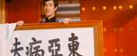 Bruce Lee holds a framed banner with black calligraphy.
