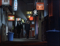 A kaleidoscope of colorful signs. in English and Japanese down a narrow alleyway, a typical scene in Ozu's films. The signs in Japanese are both in lettering and calligraphy.