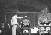 Black-and-white production photograph of two actors in an experimental control room set.