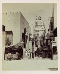 A photograph showing the entrance to the Street in Cairo immersive exhibition site at the World’s Columbian Exposition. Minarets are visible in the background. A man in a kaftan leads a horse in the foreground.
