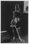 The negative image by Hans Bellmer from the series The Doll (1934) shows the doll standing against the wall, next to a painting featuring a marble. Turning its head to the side, the armless doll displays her open torso made of plaster cast with a disc mechanism fitted inside. The doll also exhibits one wooden skeleton leg and one plastered leg in full extension, covered with a white stocking.