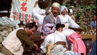 People are gathered in front of a hanging banner with red and black calligraphy.