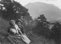 A young couple sits on the mountain slope.