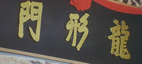 Name of the martial arts clan is written on a plaque; it might be constructed by paper cut. Gold characters on a black background.