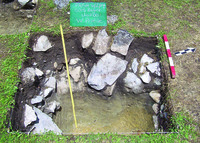 West profile photograph of Zagorë Unit 001 excavation containing rocks, dirt, and a tape measure.