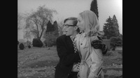 Black-and-white film still of a man holding a woman by the shoulders to show her something in the distance.