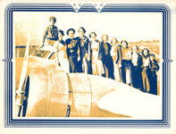 Earhart sits on the hood of the airplane cockpit in pants, while ten women in her aviation class at Purdue University stand on the wing in skirts, all with big smiles.