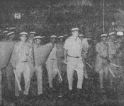 A phalanx of uniformed and helmeted policemen with riot shields and batons stand ready as an unbreakable unit to counter protestors.