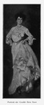 An image of a full-body portrait of Creole Dora Dean. She is dressed in a full-length dress of the Edwardian era and is wearing rings, bracelets, a large necklace, and hoop earrings. She is standing upright with a slight tilt to her left and her hands on her hips.