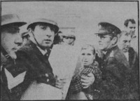 Close-­up black and white photo of helmeted Israeli policemen shoving the mother of Black Panther demonstrator Saadia Marciano in Jerusalem.