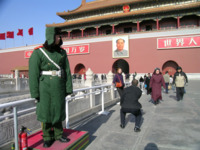 A guard stands on a plinth in Tiananmen Square, Beijing, China. A fire extinguisher sits near his right foot.