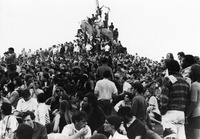 Photograph depicting students crowded around the General Logan Monument in Grant Park, Chicago, Illinois during the 1968 Democratic National Convention, August 1968. The hill is completed covered by hundreds of people densely packed together. Rows of students are standing near the horse monument to the Civil War general Logan. Some students are sitting atop the monument and several are waving flags, including one that represents the North Vietnamese communist rebels who are fighting against U.S. allies in South Vietnam.