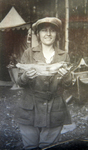 A black-and-white photograph of Mae Marshall holding a fish, a campsite is in the background.