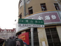 Street sign of Boshan Lu. An arrow to the left points to Shinan district, an arrow to the right points to Shibei district.