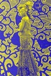 A woman wearing aso ebi against a blue and gold patterned background.