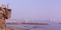 Long shot of Bhiku Mhatre (Manoj Bajpayee) standing on a cliff at the top left of the frame. Arms outstretched toward the sea, and with the Bombay skyline on the horizon, he delivers his signature line, “Mumbai ka king kaun?” in Satya.