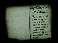 Blurry sepia-toned image of a book with old-looking font on it that reads "The Cabinet of Dr. Caligari In the year 1783, a mysticke by the name of Caligari toured the faires of numerous villages in Northern Italy, accompanied by a somnambulist named Desire…"