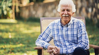 Photograph of Paul Bérenger, sitting in a chair outdoors.