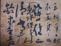 Detail photograph of a wooden board with black calligraphy.