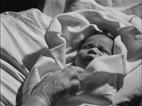 A close-up shot of an Afro-German baby wrapped in a white blanket.