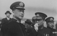This black-­and-­white photo, taken in the field, shows a group of men in military uniforms, followed by a blurred figure in civilian garb (possibly Chu Minyi). Wang Jingwei, in an admiral’s uniform and wearing a cap, is looking intently to the front left, his lips slightly parted. Sunshine casts a diagonal shadow from the cap on his face, his left eye remaining in the shadow. A fine, upward tilting wrinkle can be detected by the corner of his right eye. He seems to be deep in thought while listening to the bespectacled Ren Yuandao, who is standing to his right and covers his mouth with a gloved fist, looking intently to the left while speaking. Distant hills can be seen in the background.