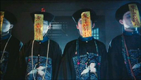 A line of individuals have streamers attached to their hats covering their faces with red calligraphy.