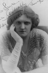 Autographed portrait of May Tully. Wearing an embroidered gown and white opera gloves, Tully leans on one arm with a forthright expression.