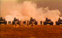 A shot from Buddha Bless America showing six kids running in front of a line of tanks and accompanying soldiers in a field exercise.