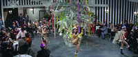 Extreme long shot, high-­angle, of a semi-­circular dancing floor. In the center of the performance, a Christmas “tree”: made entirely of tinsel with hardly any green. Fanning out from it are three semi-­nude dancers in fur-­lined, santa-­esque costume. The incongruous gray, quasi-­modernist walls and the audience make up the background.