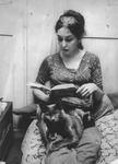 Carolee Schneemann reading with cat Kitch in her lap.