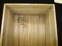 Detail photograph of a wooden box interior with black calligraphy and red seal.