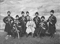 Portrait of three Cossack men sitting in front of five Cossack men, in front of a painted backdrop. The men wear hats, traditional Georgian chokhas, swords and daggers.