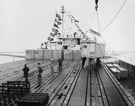 Workers help maneuver a container to the appropriate location on the ship’s deck.