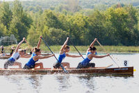 A color photograph of a women's competitive canoe team paddling through water.