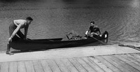 A black-and-white photo of Sevareid and Port getting into a canoe from a wooden pier.