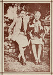 Photo shows the two sitting on a stone wall dressed in skirts and jackets. Hall wears a tie. Hall's arm is slipped under her partner's arm, touching Troubridge's hand.