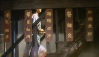 A woman climbs a wooden stairway, obscured by hanging calligraphic planks.