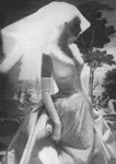 A black-­and-­white photograph of a woman in a luminous wedding dress