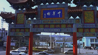 White calligraphy is written on a blue placard above a gateway entrance.