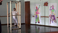 Color screenshot from a documentary film showing one male adult with Down syndrome practicing part of a performance in a dance studio whose walls are lined with mirrors.