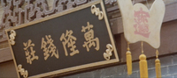 Calligraphy is visible on a hanging board and a sign.