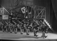 A row of actors, identically clad in prozodezhda (utilitarian uniform costumes), bowing in unison, traverse the forestage in front of Liubov Popova’s constructivist playground of a set.