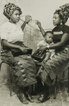 Two women wearing cotton print wrappers with mat pattern.