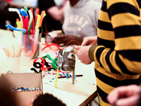 Photograph of several students using duct tape, pipe cleaners, popsicle sticks, and other craft supplies in a Maker workshop.