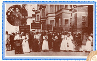 Nine women hold signs on a crowded street in 1910. The signs protest child labor and promote unions and organizing. One woman carries the WTUL flag. A crowd of men gathers in the background.